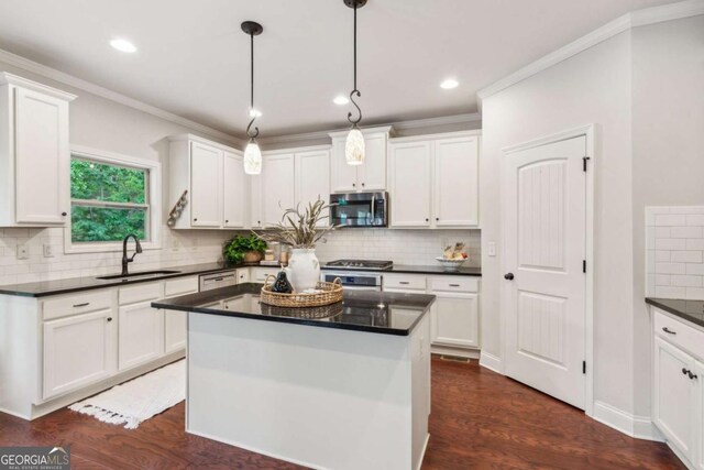 kitchen with a sink, appliances with stainless steel finishes, dark countertops, white cabinetry, and recessed lighting
