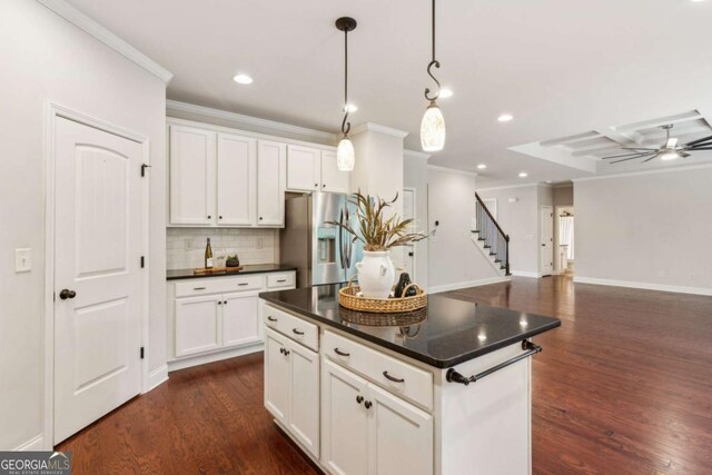 kitchen featuring stainless steel fridge with ice dispenser, dark countertops, crown molding, decorative backsplash, and white cabinets