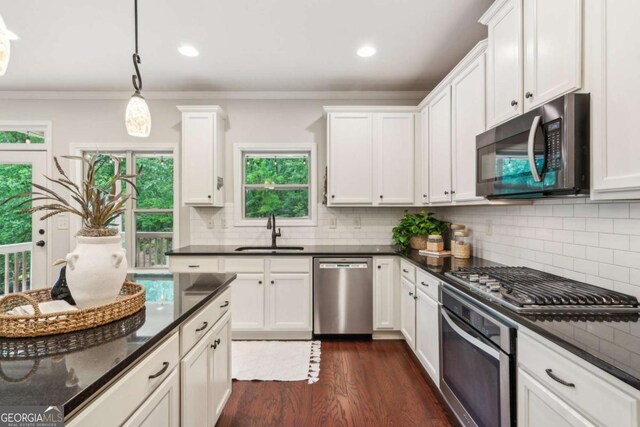 kitchen featuring stainless steel appliances, a sink, white cabinetry, tasteful backsplash, and dark wood finished floors