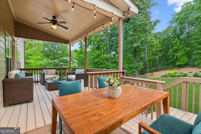deck featuring an outdoor hangout area, ceiling fan, view of scattered trees, outdoor dining area, and a yard