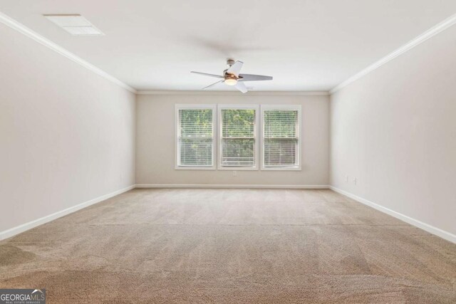 spare room with crown molding, a ceiling fan, carpet floors, and baseboards