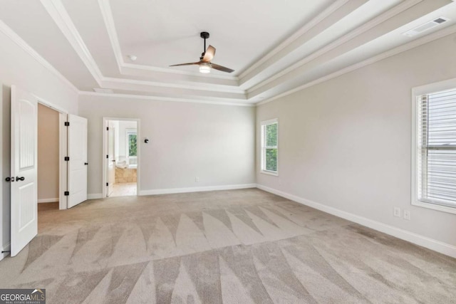 spare room with crown molding, ceiling fan, light colored carpet, a raised ceiling, and baseboards