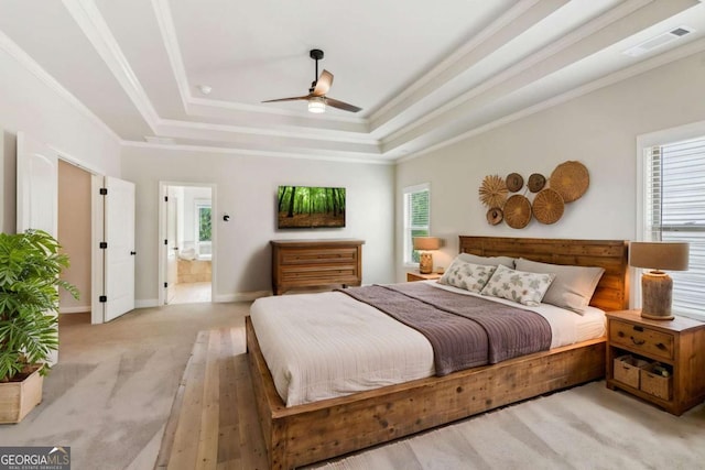 bedroom with ornamental molding, light carpet, a raised ceiling, baseboards, and ensuite bath