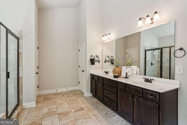 bathroom with a stall shower, a high ceiling, baseboards, and double vanity