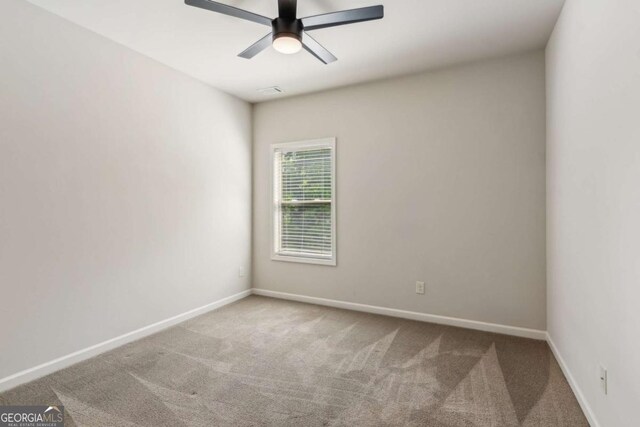 carpeted spare room with ceiling fan and baseboards