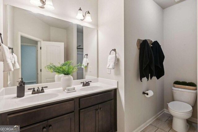 full bathroom with toilet, double vanity, tile patterned floors, and baseboards
