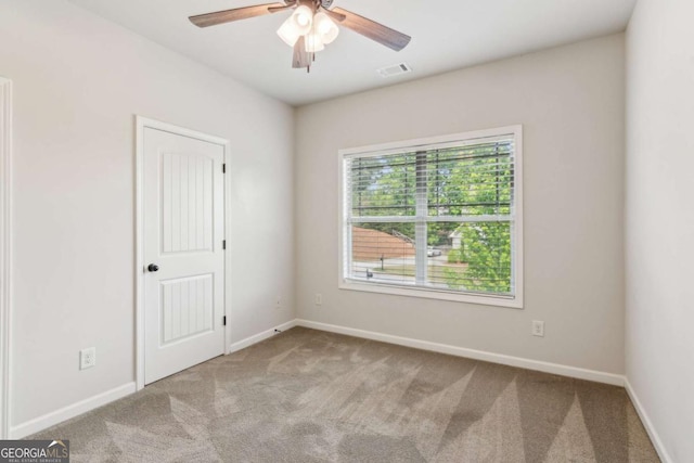 carpeted spare room with a ceiling fan and baseboards
