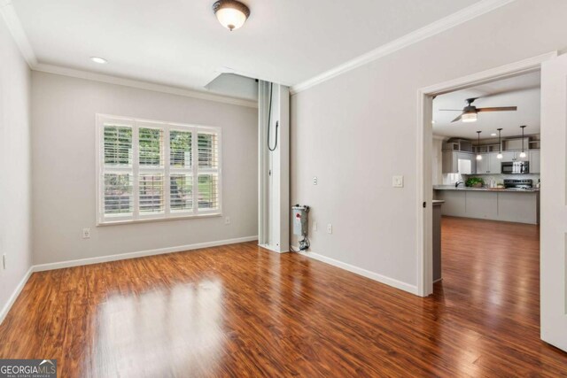 unfurnished living room with a ceiling fan, crown molding, wood finished floors, and baseboards