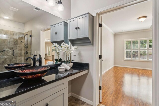 full bath featuring a stall shower, vanity, crown molding, baseboards, and wood finished floors