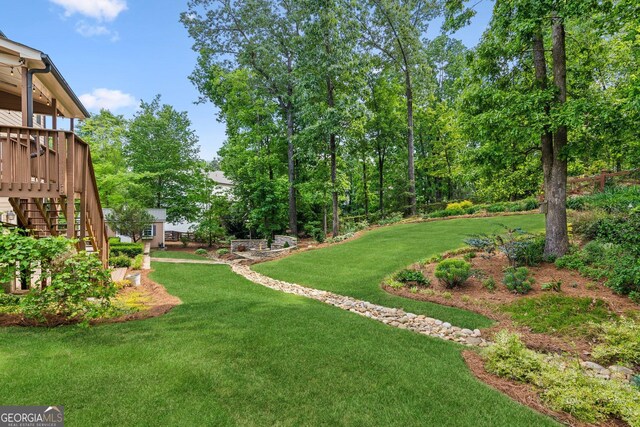 view of grassy yard with stairway and a wooden deck