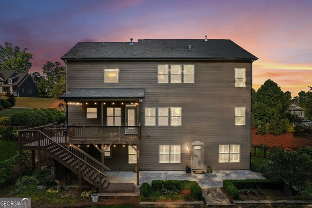 back of property at dusk with a patio, a deck, and stairs
