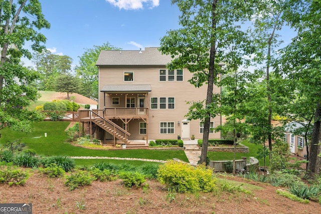 rear view of house with stairway, a deck, and a lawn