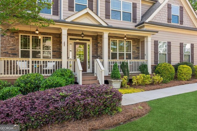 doorway to property featuring a porch and stone siding