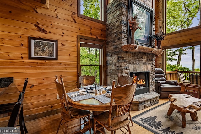 dining room featuring wood finished floors, wood walls, and a fireplace