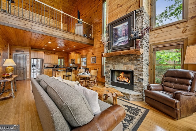 living room with wooden walls, a high ceiling, light wood-style floors, and a fireplace