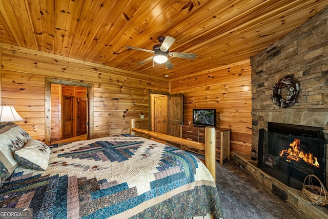 bedroom with a stone fireplace, carpet, wooden ceiling, wooden walls, and ceiling fan