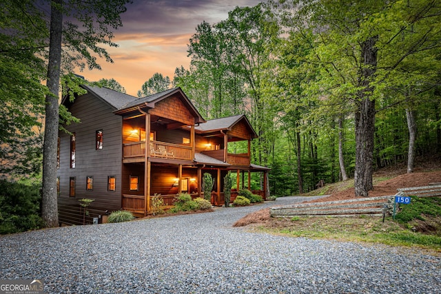 view of front of property featuring a balcony, covered porch, driveway, and a shingled roof