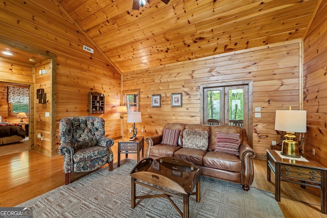 living area with vaulted ceiling, wood finished floors, wooden walls, and wooden ceiling