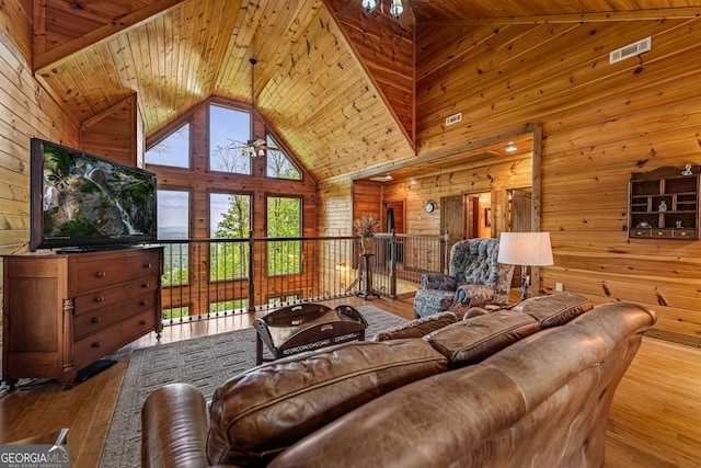 living room with wooden walls, wood ceiling, high vaulted ceiling, hardwood / wood-style flooring, and a ceiling fan
