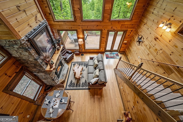 unfurnished living room with a lit fireplace, wood walls, and wood finished floors