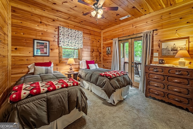carpeted bedroom featuring access to exterior, wood walls, wooden ceiling, and a ceiling fan