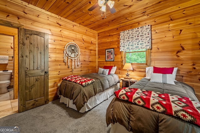 carpeted bedroom featuring wood walls, connected bathroom, wooden ceiling, and a ceiling fan