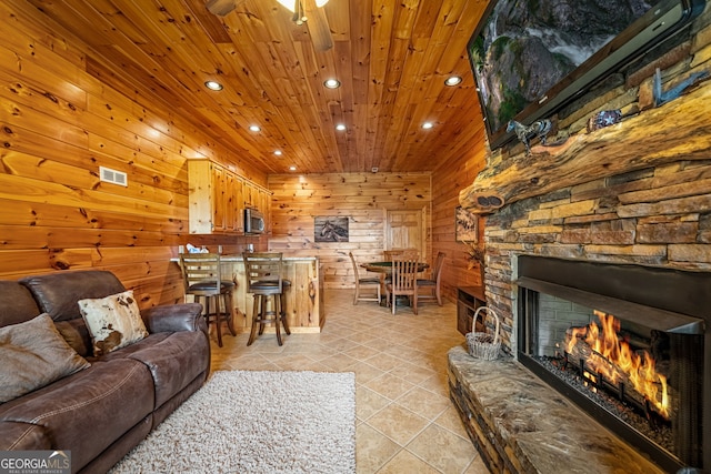 living area with light tile patterned floors, recessed lighting, wood ceiling, wooden walls, and a fireplace