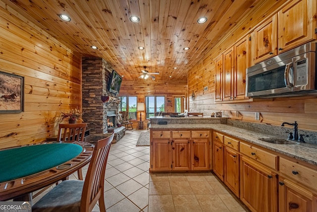 kitchen with stainless steel microwave, a peninsula, recessed lighting, wood ceiling, and a fireplace