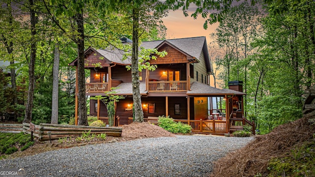 view of front of home featuring a balcony, covered porch, and roof with shingles