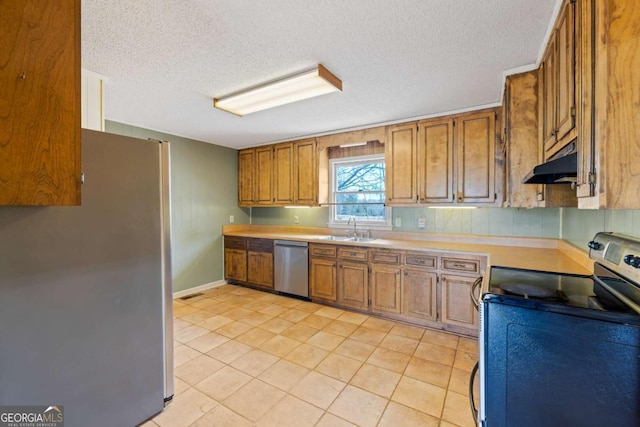 kitchen featuring stainless steel appliances, under cabinet range hood, a sink, brown cabinets, and light countertops