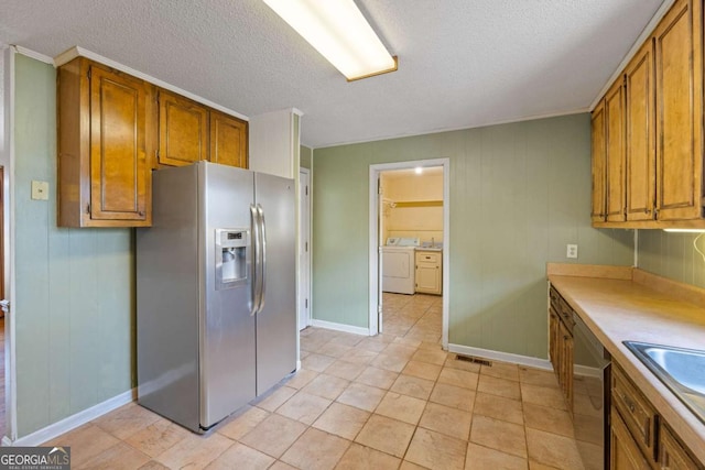 kitchen featuring appliances with stainless steel finishes, brown cabinets, a textured ceiling, and baseboards