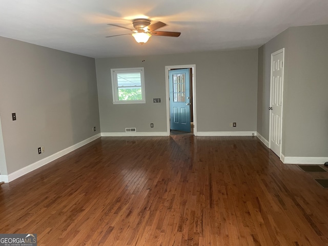 empty room featuring ceiling fan, baseboards, and dark wood-style floors