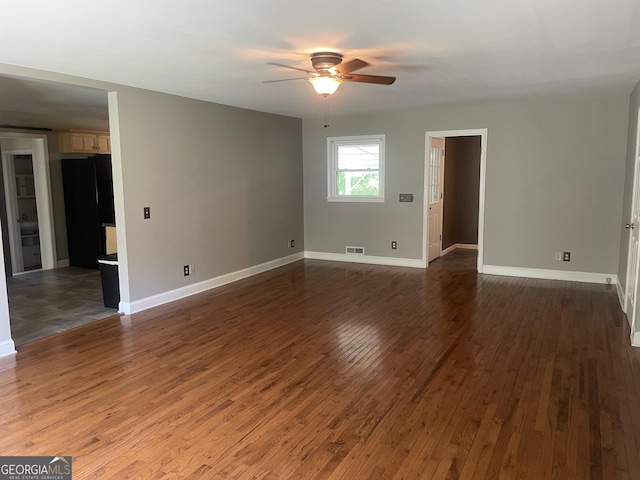 empty room featuring ceiling fan, dark wood-style flooring, and baseboards