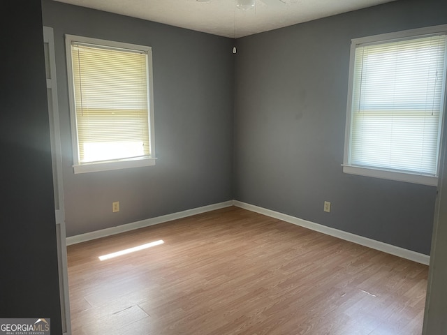 unfurnished room featuring wood finished floors, healthy amount of natural light, ceiling fan, and baseboards