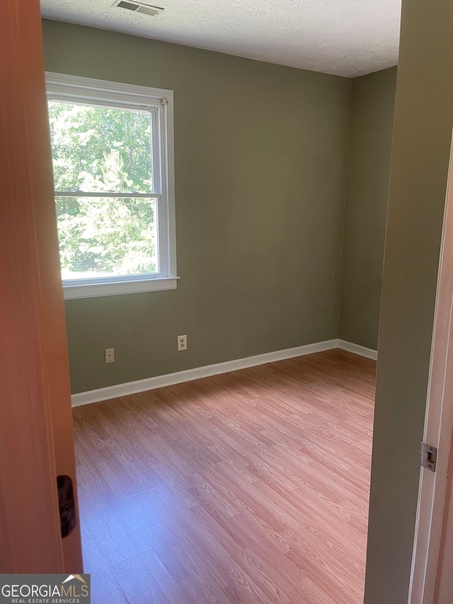 unfurnished room featuring wood finished floors, a textured ceiling, and baseboards