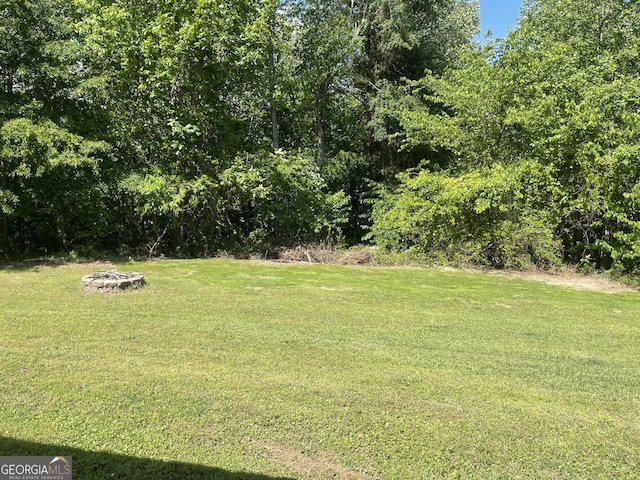 view of green lawn featuring an outdoor fire pit
