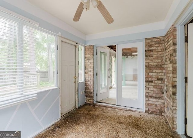 unfurnished room featuring brick wall and ceiling fan