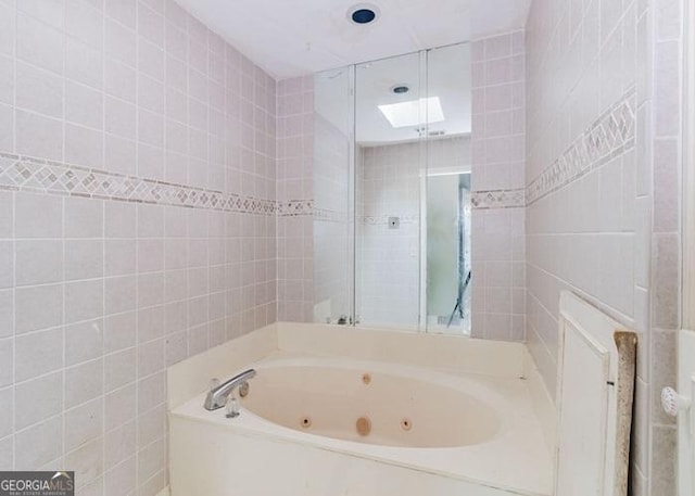 bathroom with a whirlpool tub and tile walls