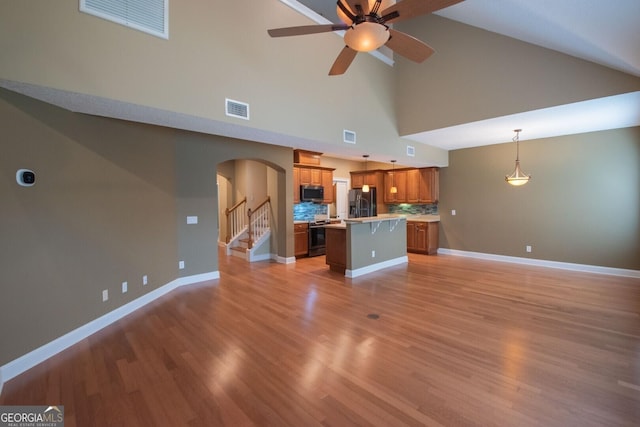 unfurnished living room featuring high vaulted ceiling, arched walkways, ceiling fan, baseboards, and light wood-type flooring