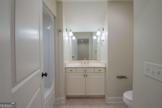 bathroom featuring toilet, vanity, tile patterned flooring, and baseboards