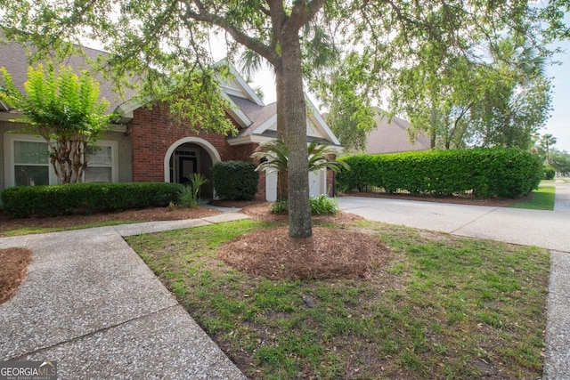view of front of house featuring brick siding, roof with shingles, and driveway