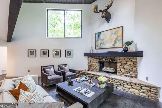 living room featuring a towering ceiling, a stone fireplace, and baseboards