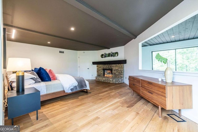 bedroom featuring light wood finished floors, beam ceiling, a fireplace, and recessed lighting