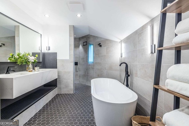 full bath with tile walls, a freestanding bath, a walk in shower, tile patterned floors, and double vanity