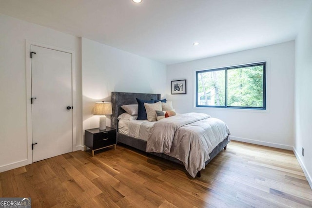 bedroom with wood finished floors, recessed lighting, and baseboards
