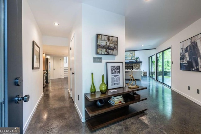 corridor featuring baseboards, concrete flooring, and recessed lighting