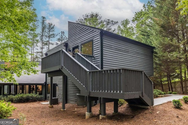 back of house with a deck, fence, and stairway