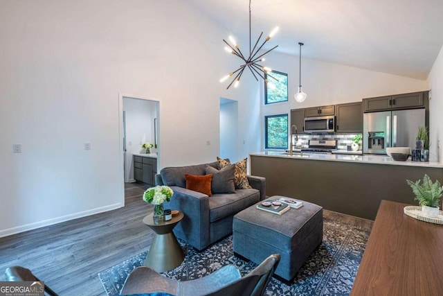 living area with a chandelier, dark wood-style flooring, high vaulted ceiling, and baseboards