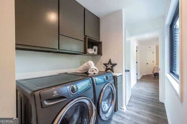clothes washing area with wood finished floors, independent washer and dryer, cabinet space, and baseboards