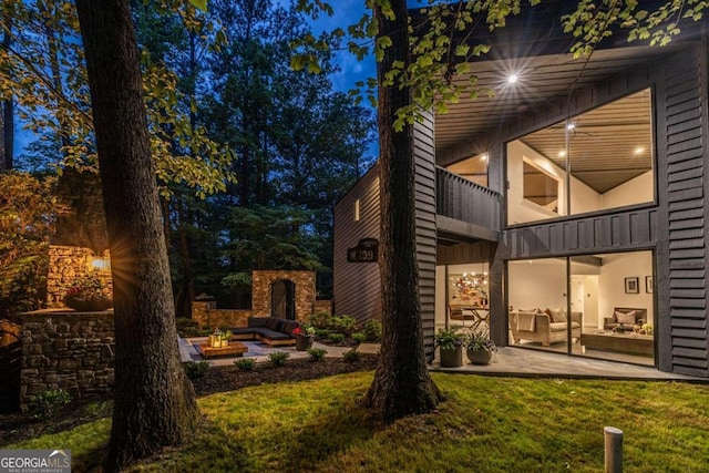 rear view of house with a patio, an outdoor living space, a balcony, and a yard